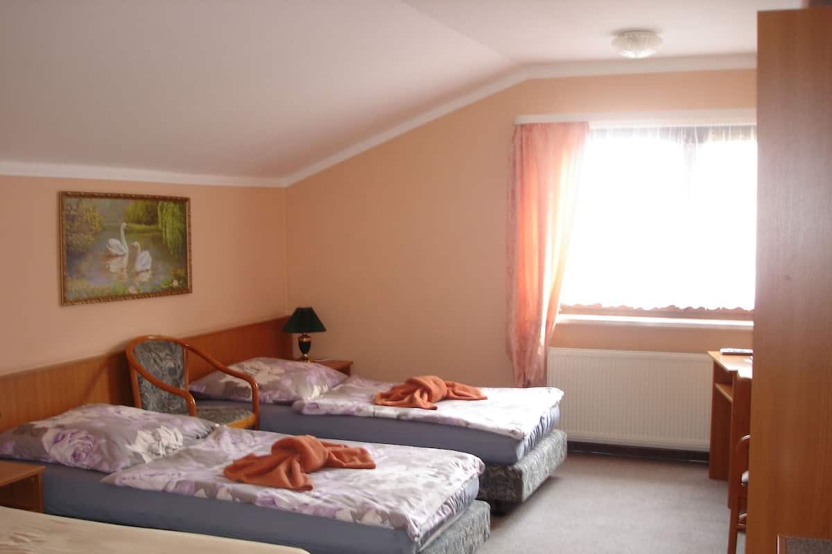 Een slaapkamer met twee bedden, een bureau, een stoel, een lamp en een schilderij aan de muur.