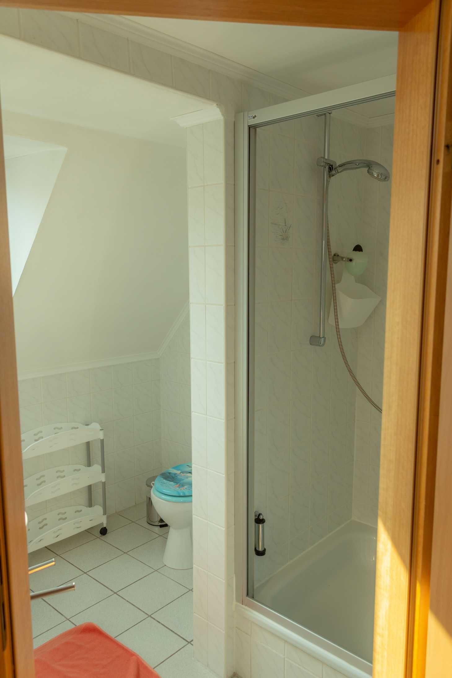 A bathroom with a glass-enclosed shower, a toilet, and a white tiled floor.