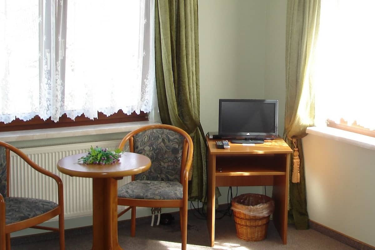 Een gezellige kamer met een houten tafel, twee stoelen, een televisie op een standaard en een radiator.