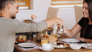 Una mesa de comedor con alimentos para el desayuno, como una ensalada de frutas, croissants y una taza de café.