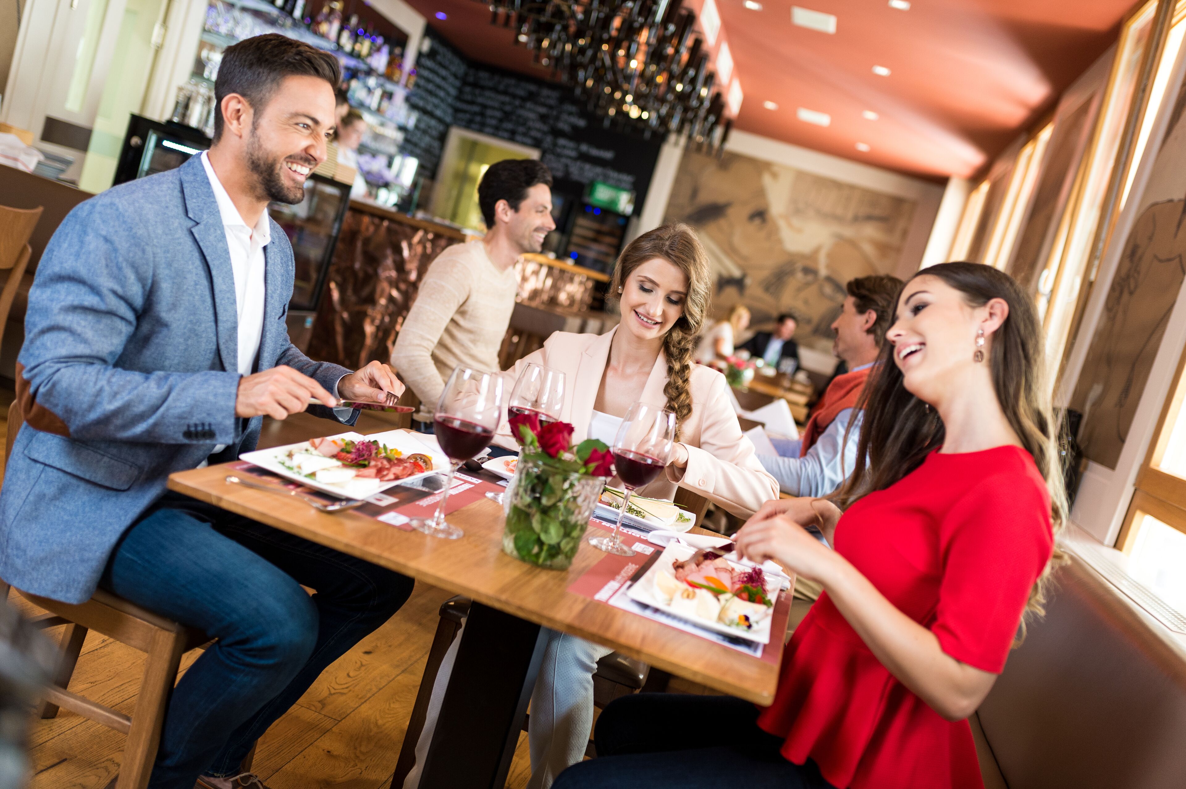 A group of people dining at a restaurant with a bar in the background.