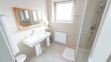 A modern bathroom with a sink, mirror, and shower.