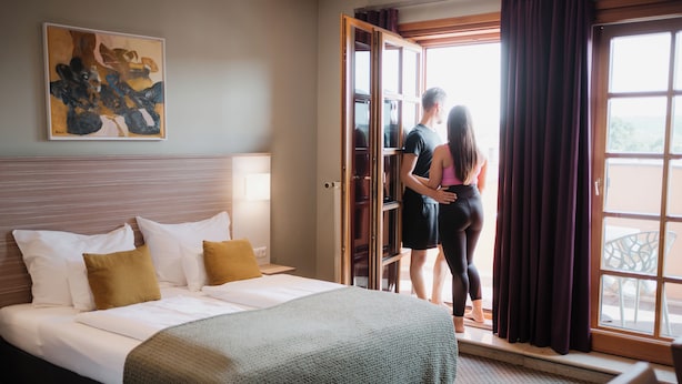 Una habitación de hotel con cama, ventana y puerta que da a un balcón.