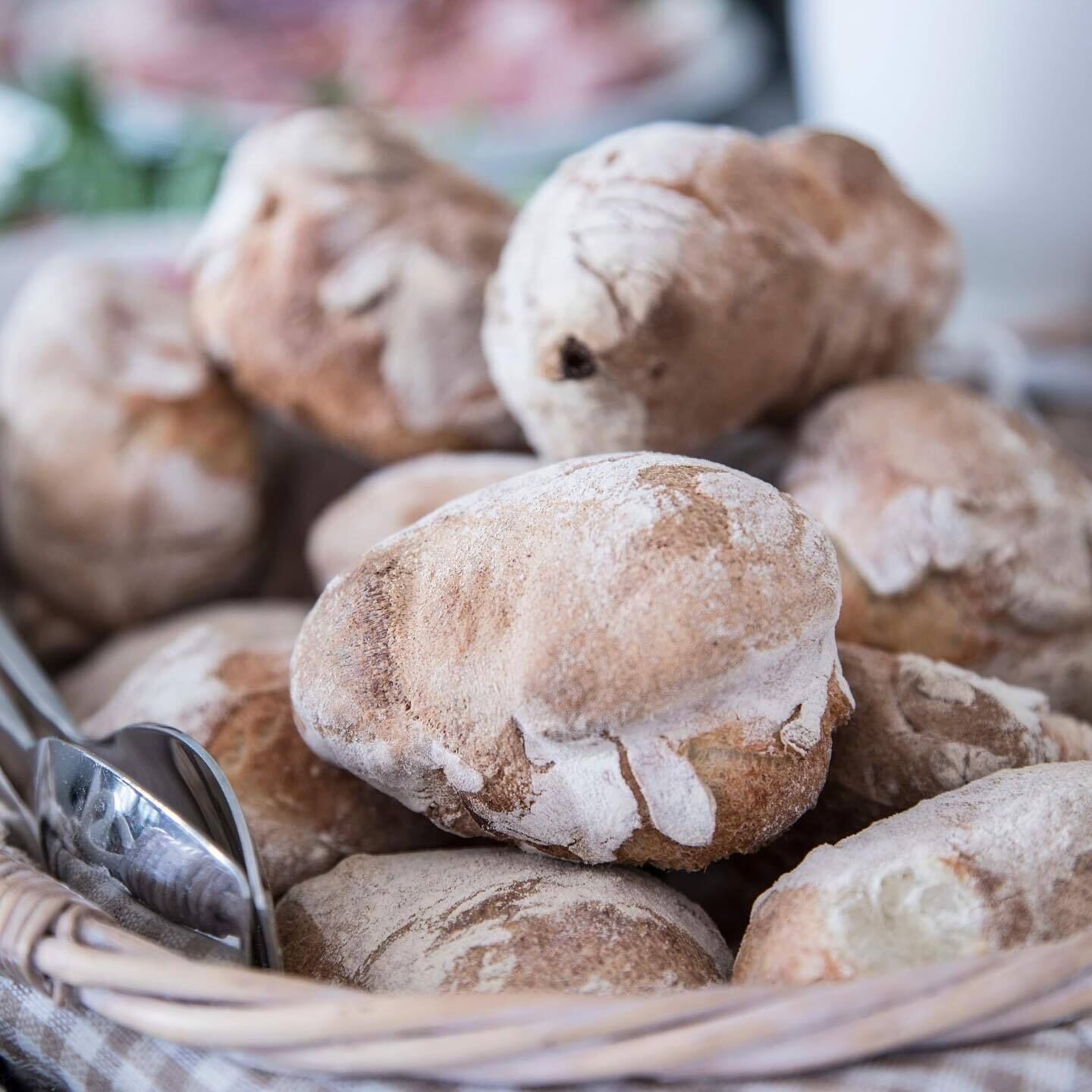 Ein Korb voller runder, mit Staub bestreuter Brötchen.