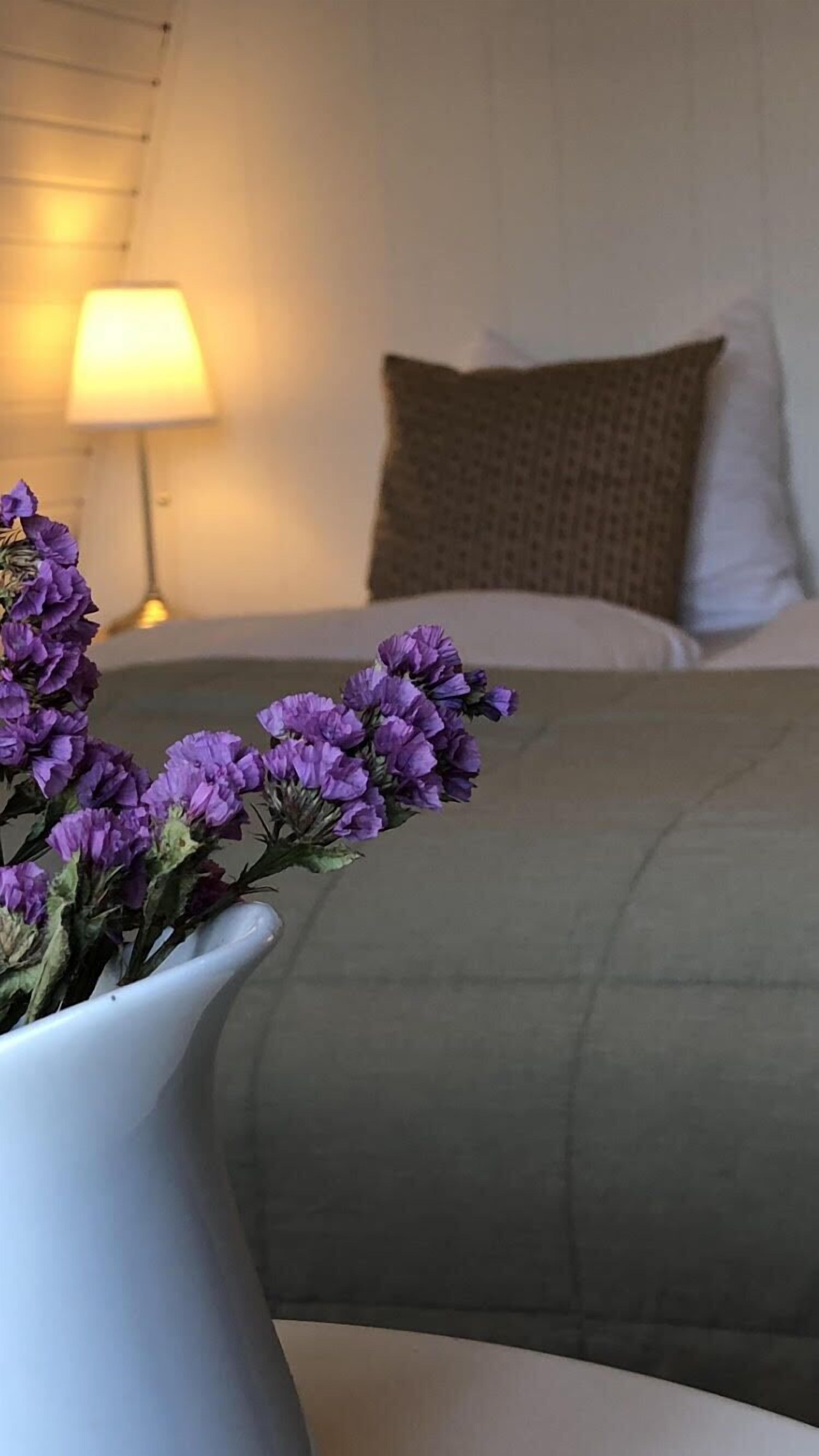 Ein Bett mit einem grünen Überwurf, einem weißen Kopfkissen und einem braunen Kopfkissen.