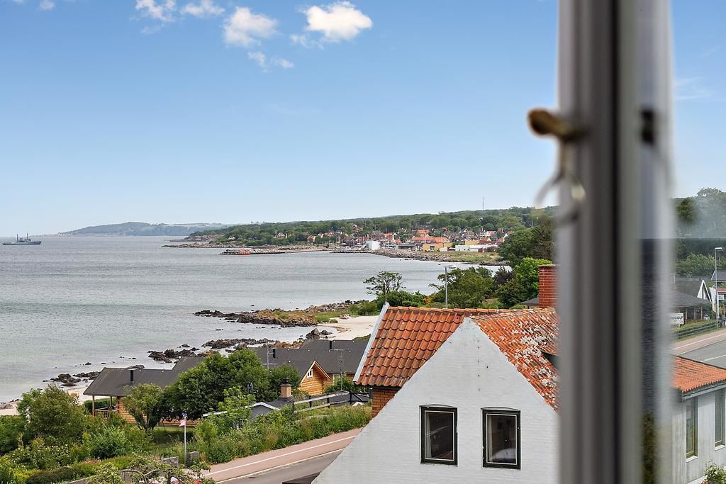 A coastal town with a view of the sea and a prominent white building with a red roof.