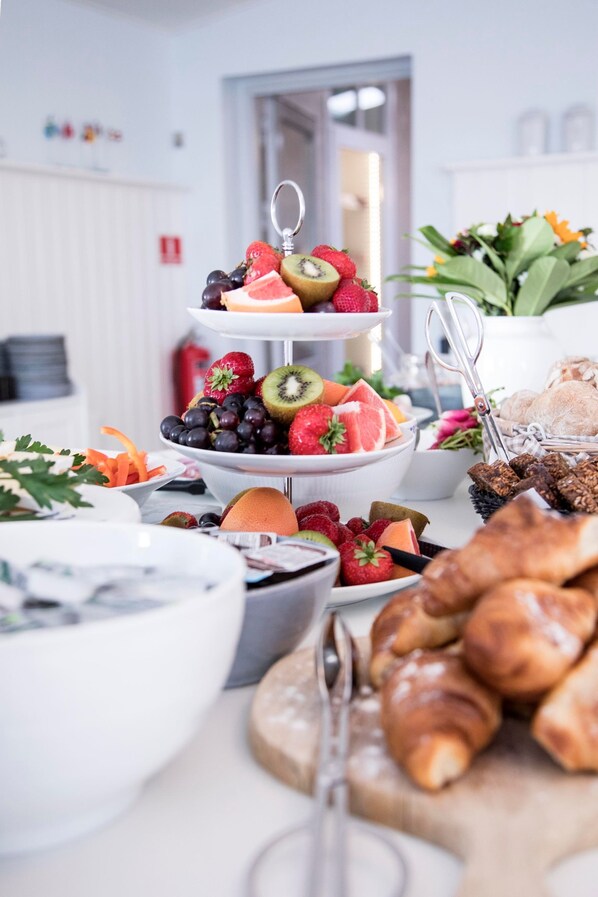 A three-tiered fruit and pastry display with various fruits and pastries. - Sandkaas Badehotel (Allinge)
