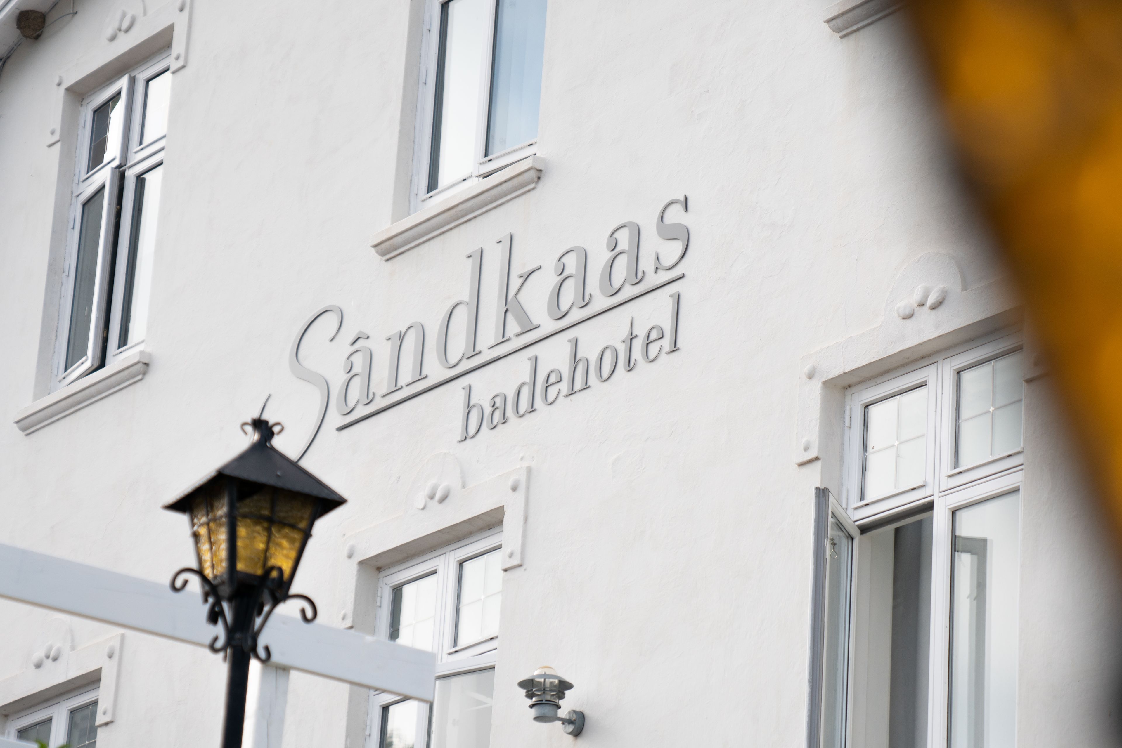 Ein Gebäude mit einem Schild, auf dem „Sandkaas badehotel“ steht.