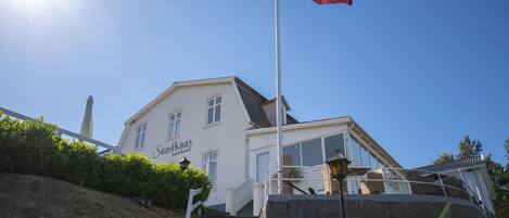 A building with a flagpole, a staircase, and a sign that reads "Sanukaa's Bædhotel".