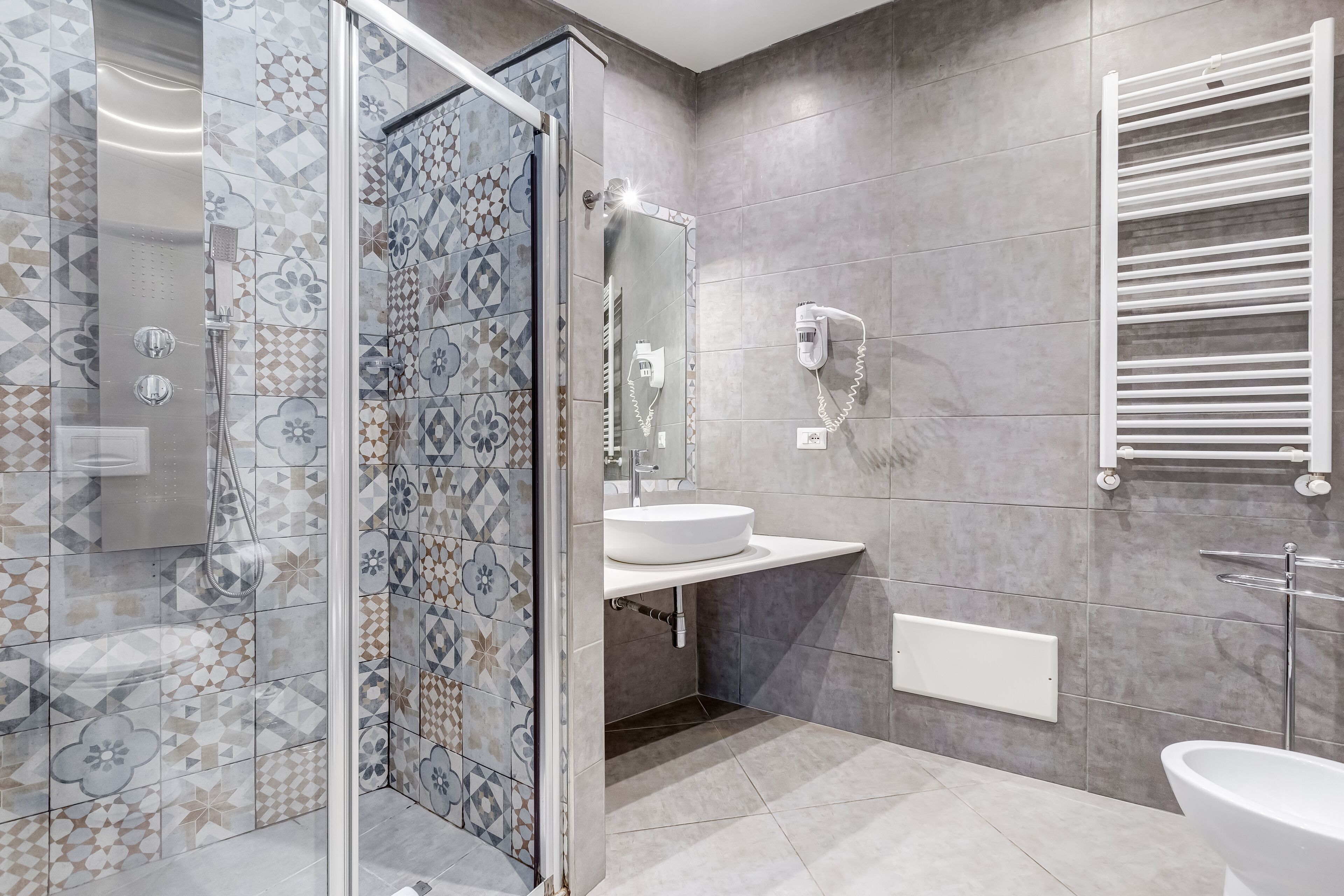 Une salle de bain moderne avec une douche à parois de verre, un lavabo blanc et un porte-serviettes.