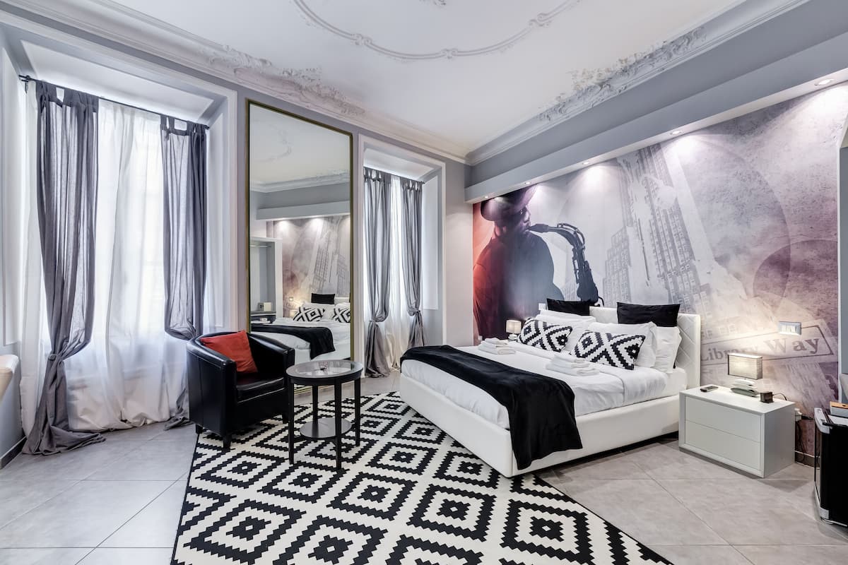 A modern bedroom with a large bed, a side table, a chair, and a large mirror.