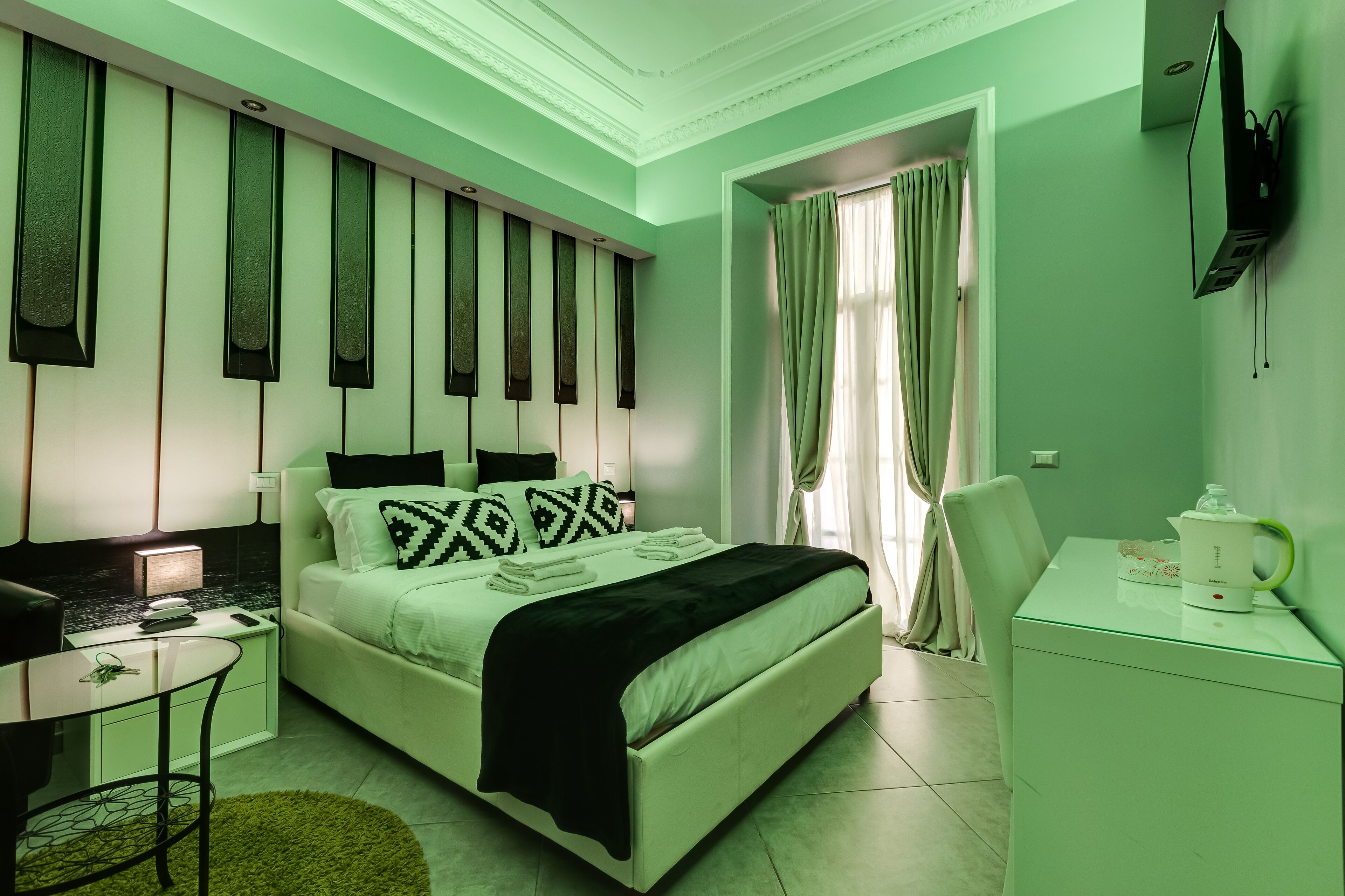 A modern bedroom with a bed, bedside table, and a desk with a kettle.