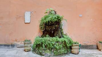 Una jardinera de piedra con plantas verdes exuberantes frente a una pared naranja.