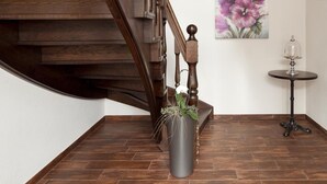 A wooden staircase with a dark finish, a potted plant, and a painting of flowers on the wall. - Zu den Drei Linden (Wermelskirchen)