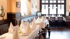 A restaurant with long tables set for dining, featuring white tablecloths and napkins. - Zu den Drei Linden (Wermelskirchen)