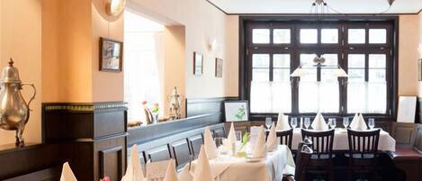 Un restaurante con mesas largas dispuestas para comer, destacando manteles y servilletas blancos.