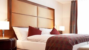 A hotel room with a large bed, two bedside tables, a nightstand, and a window with curtains. - Zu den Drei Linden (Wermelskirchen)
