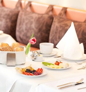 A breakfast setting with croissants, fruit, and a white teapot. - Zu den Drei Linden (Wermelskirchen)