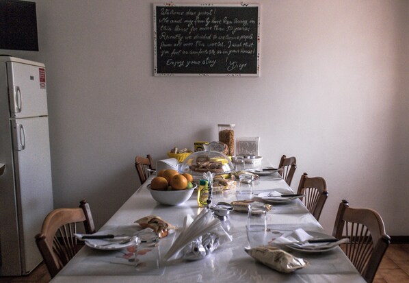 Una mesa de comedor servida con platos, tazones y diversas opciones de comida, con un letrero de pizarra encima.