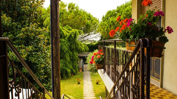 A garden pathway leading to a house with a wooden staircase and metal railings. - Airport Venice Diego 2 (Mestre)