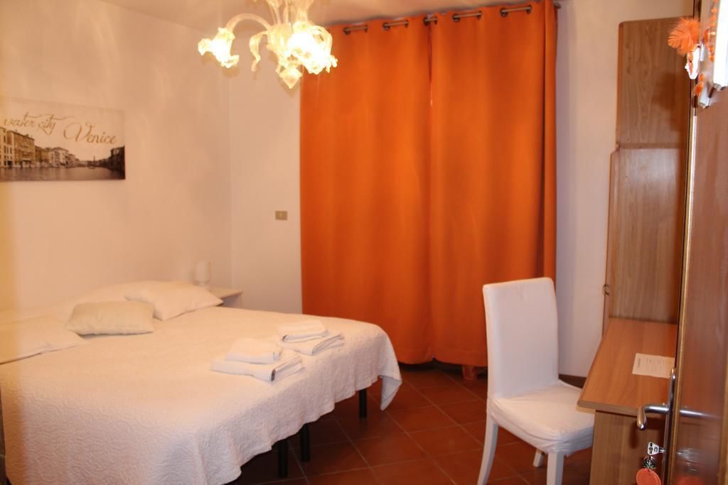 A hotel room with a bed, a chair, a shower area, and a curtain.