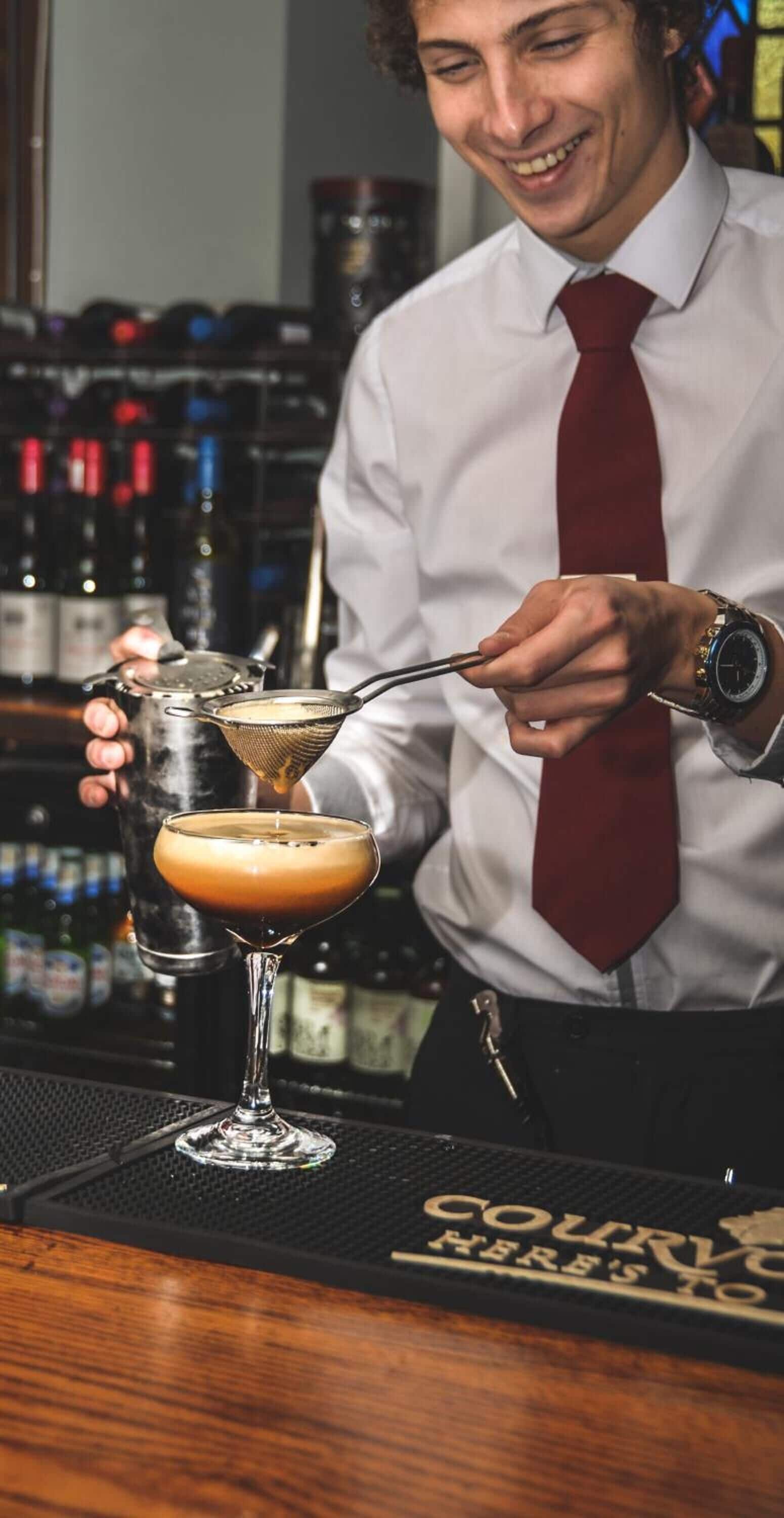 Un barista prepara un cocktail con un colino.