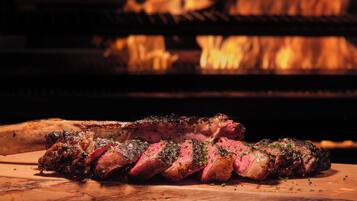 A steak being cooked on a grill with a fire in the background.