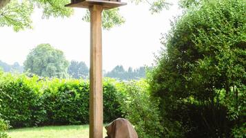 A birdhouse on a wooden post in a garden with a statue of a person.
