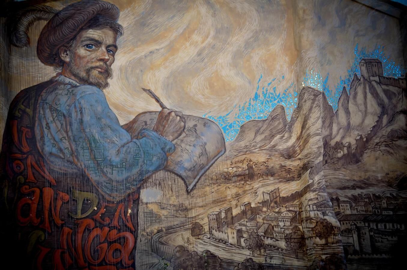 A mural of a person painting a landscape with mountains and a village.