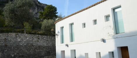 Un bâtiment blanc avec de nombreuses fenêtres et un mur en pierre.