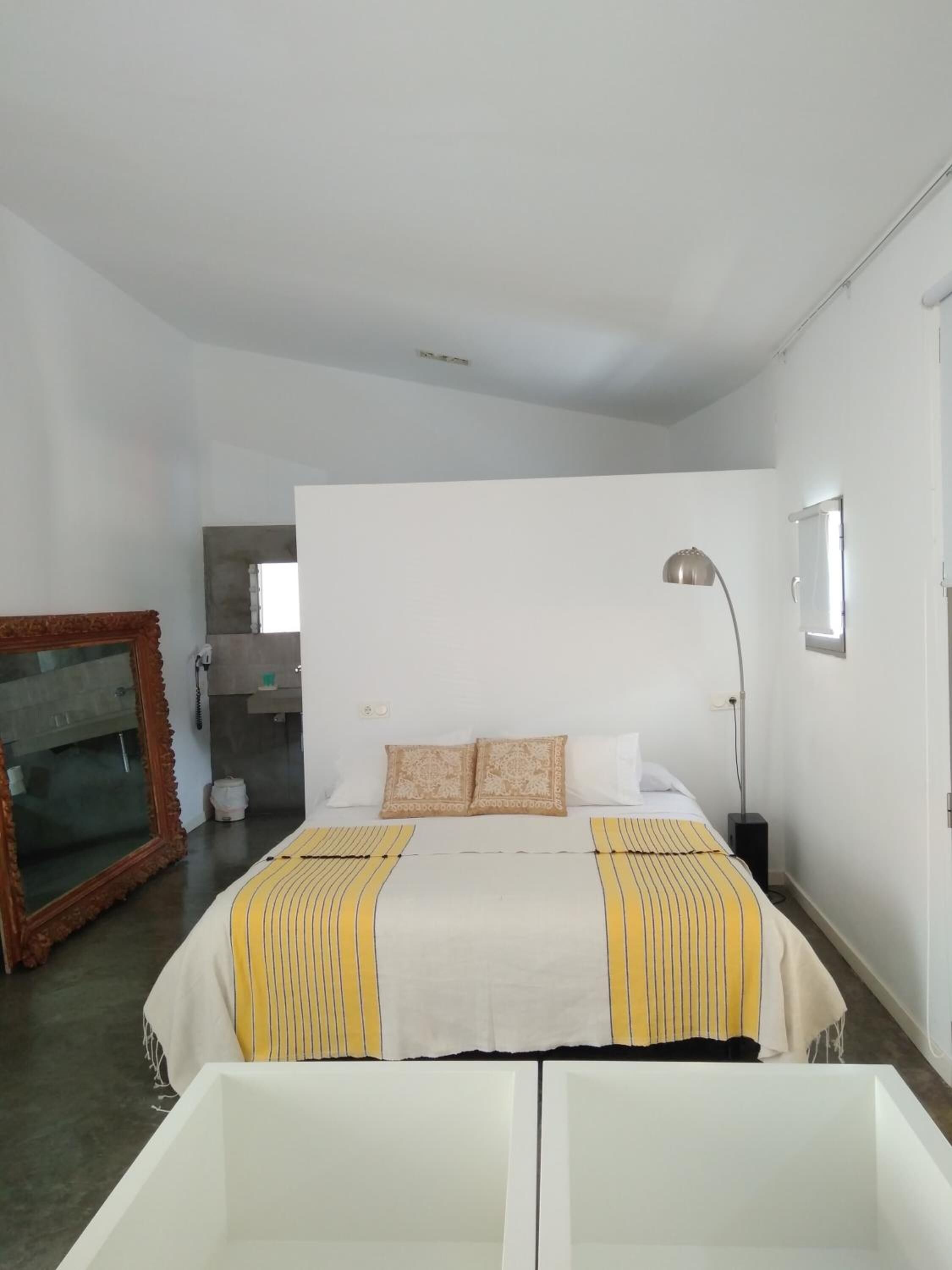 Ein schlichter Schlafzimmer mit Bett, Nachttischlampe und Spiegel.