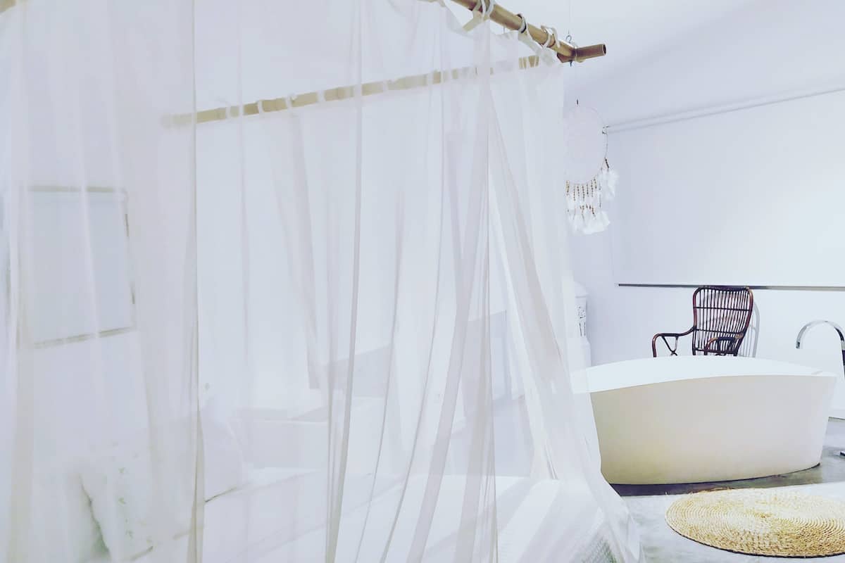 Une salle de bain moderne avec une grande baignoire, une chaise en bois et un tapis tissé sur le sol.