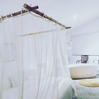 Un baño moderno con una bañera grande, una silla de madera y un tapete tejido en el suelo.