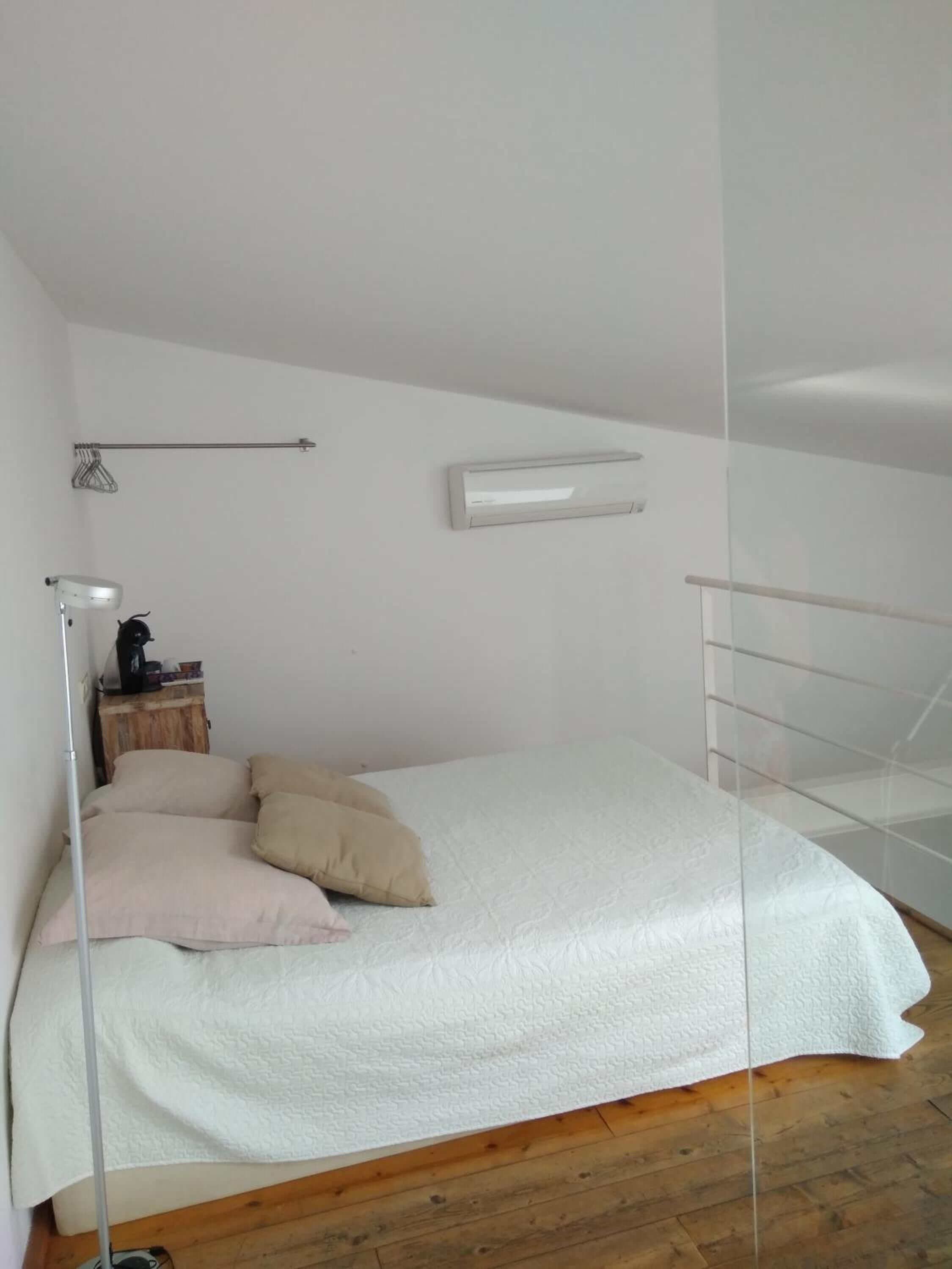 Un dormitorio con cama, mesita de noche, lámpara y ventana.