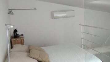Un dormitorio con cama, mesita de noche, lámpara y ventana.