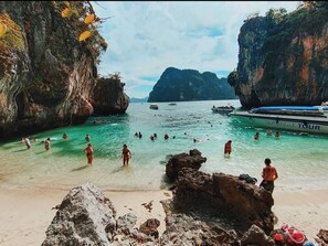A beach with clear turquoise water, rocky formations, and a boat named 'SEA EAGLE TOUR' in the background. - Aonang Hill @ 11/1 (Krabi)