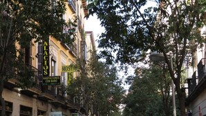 A busy street with buildings, signs for 'Alacios' and 'Hostal', and pedestrians.