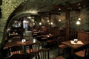An interior with stone walls, wooden tables, and hanging lights. - Hotel Tilia (Pezinok)