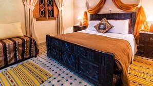 A traditional room with a bed, curtains, a window, and a patterned rug. - Riad Bab Tilila (Marrakech)
