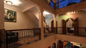 A multi-level interior with a staircase, balconies, and a painting on the wall. - Riad Bab Tilila (Marrakech)