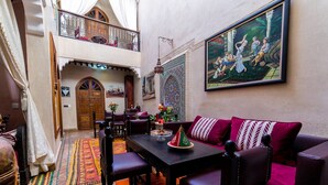 A traditional Moroccan interior with a dining area, a balcony, and a large painting. - Riad Bab Tilila (Marrakech)