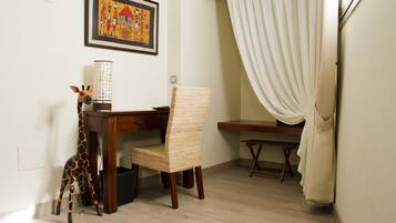 A room with a wooden desk, a wicker chair, a giraffe figurine, and a framed picture on the wall.