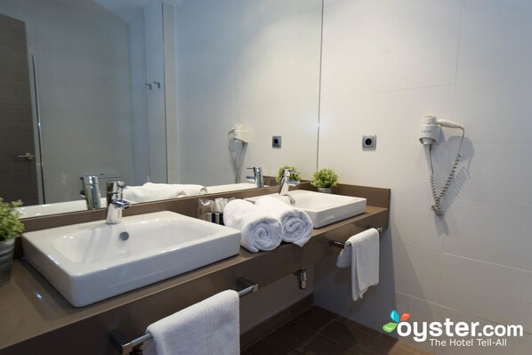 A modern bathroom with two sinks, a large mirror, and a hairdryer on the wall.