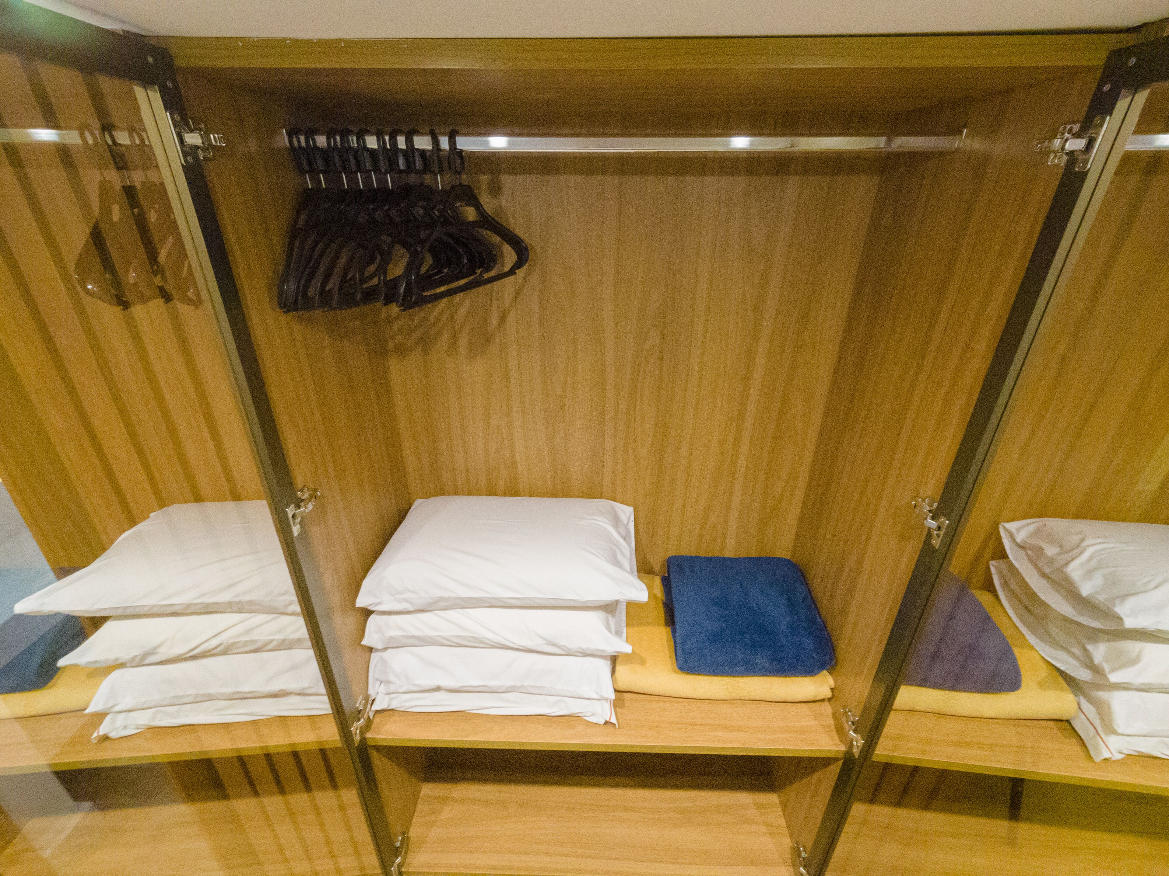 A wooden room with two beds, each with a pillow and a folded blanket.
