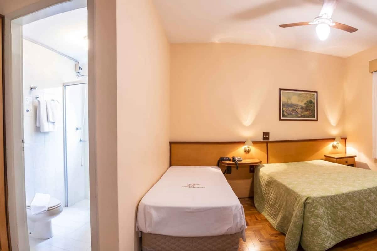 Ein Hotelzimmer mit zwei Betten, einer Dusche, einem Wandbild und einem Deckenventilator.