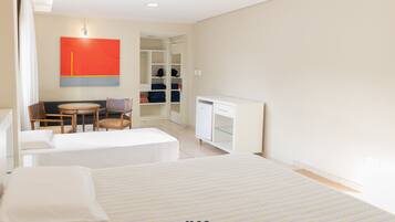 A hotel room with two beds, a desk, a chair, and a wardrobe.