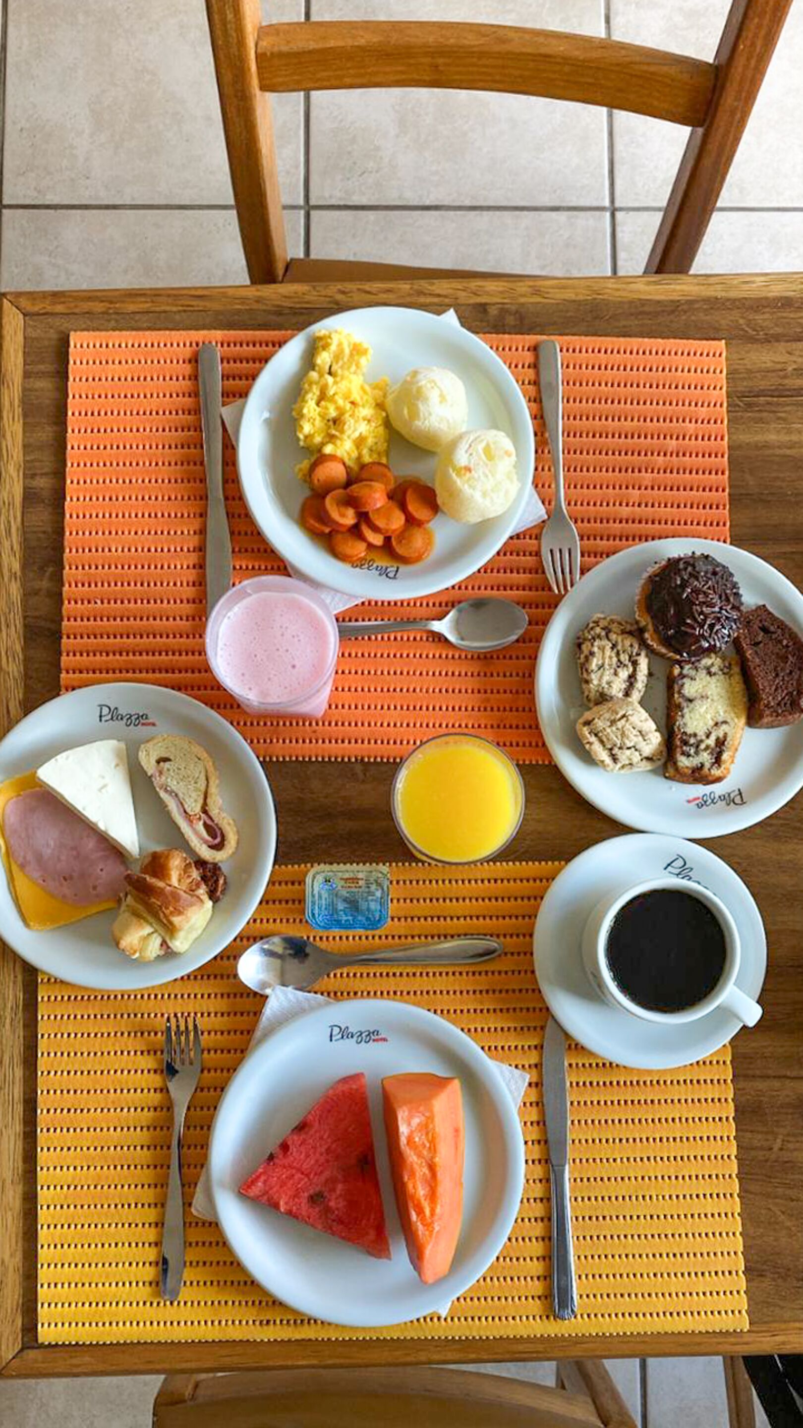 A breakfast table with plates of food, including eggs, sausage, toast, and fruit.