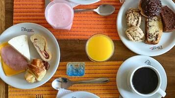 A breakfast table with plates of food, including eggs, sausage, toast, and fruit.
