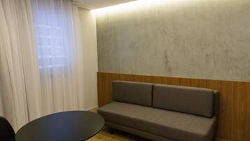 Una habitación moderna con un sofá gris, una pequeña mesa redonda y un revestimiento de pared de madera.