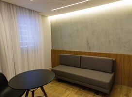 Una habitación moderna con un sofá gris, una pequeña mesa redonda y un revestimiento de pared de madera.